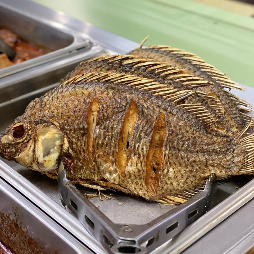 Two whole fried fish, golden brown and crispy, resting in a metal serving tray.