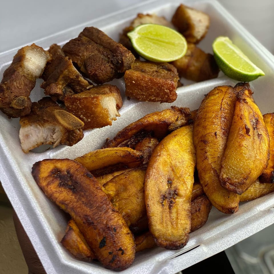 Ana Restaurant's fried pork chunks and sweet plantains with lime wedges in a white takeout container.
