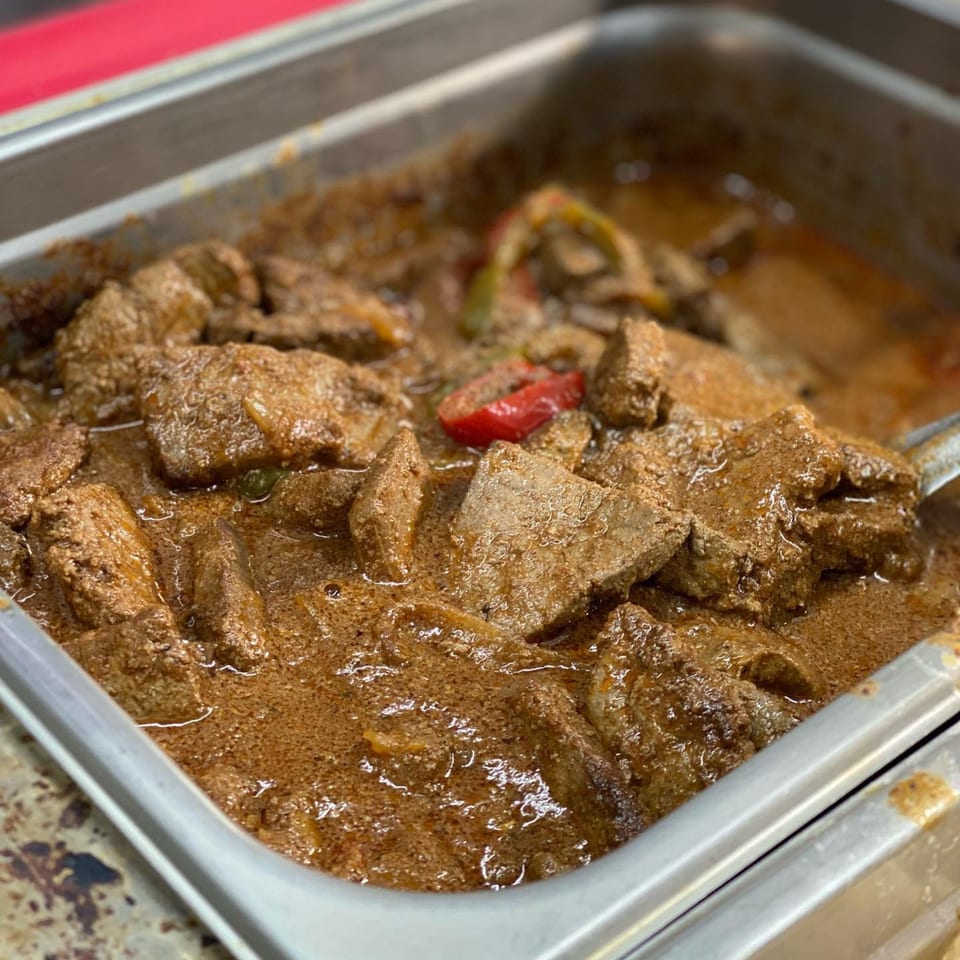 Close-up of Ana Restaurant's savory brown stew with chunks of meat and red pepper slices.